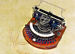 Mquina de escribir americana Hammond (1895). Base de madera, y teclado semicircular.